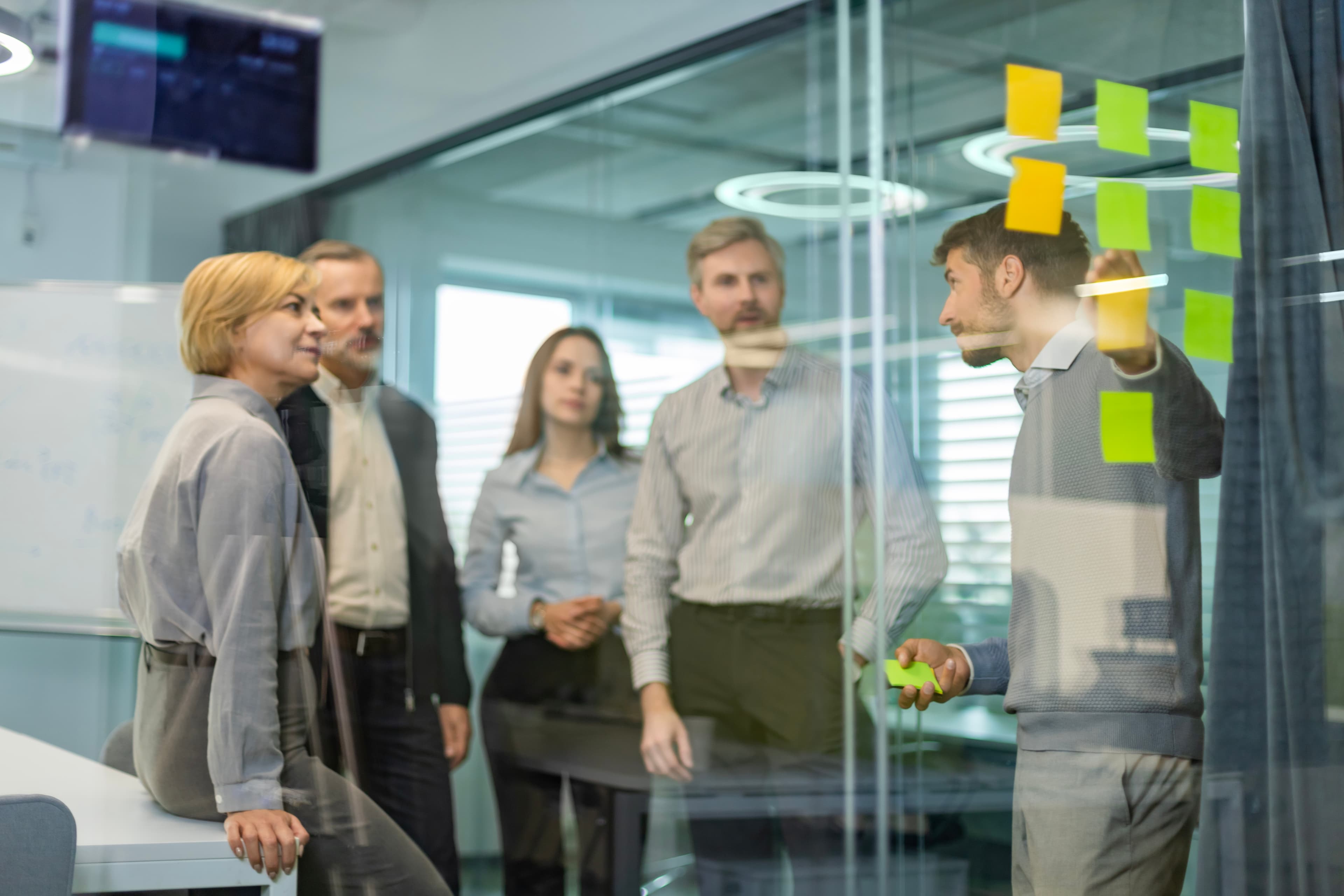 group brainstorming with sticky notes on a glass door