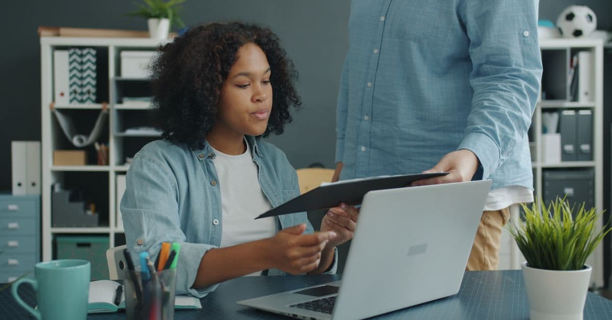 Two property team members review a laptop and documents together at an office table.