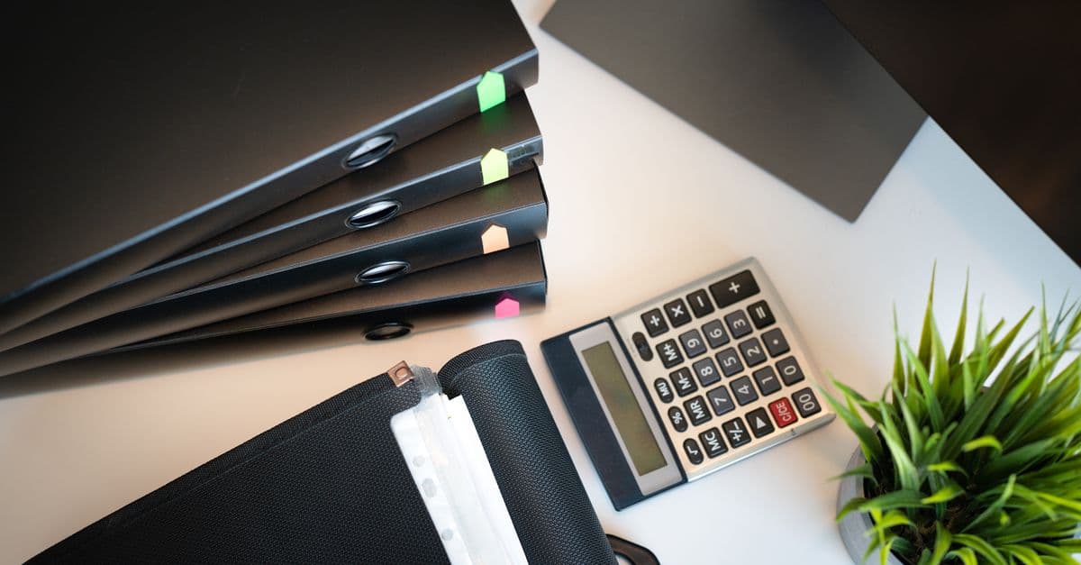 An organized desk with tenant file folders, a calculator, and paperwork laid out for review before an audit.
