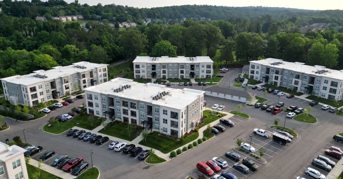 Aerial view of a low-rise, well-kept apartment community with landscaped grounds and parking, the kind of income-restricted housing this software manages.